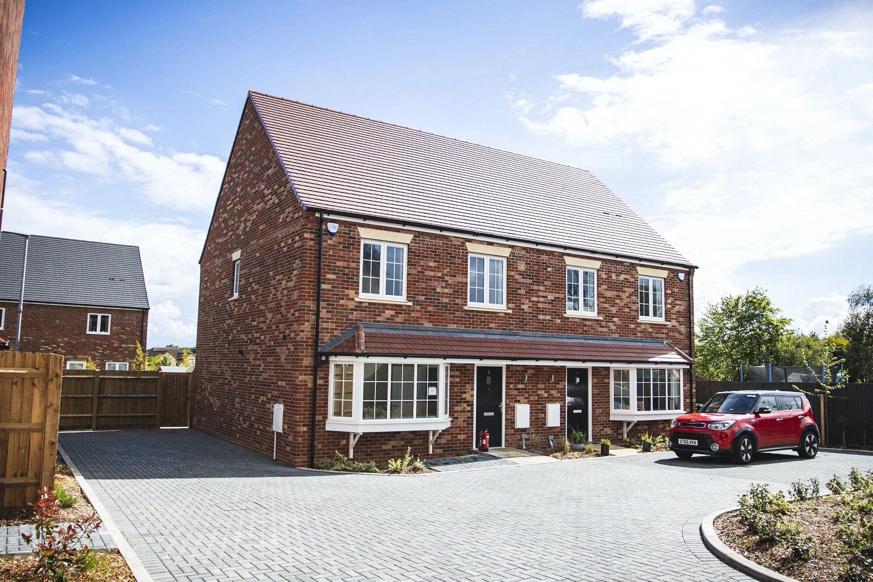 A finished I.C Developments new-build home with a paved driveway under a blue sky