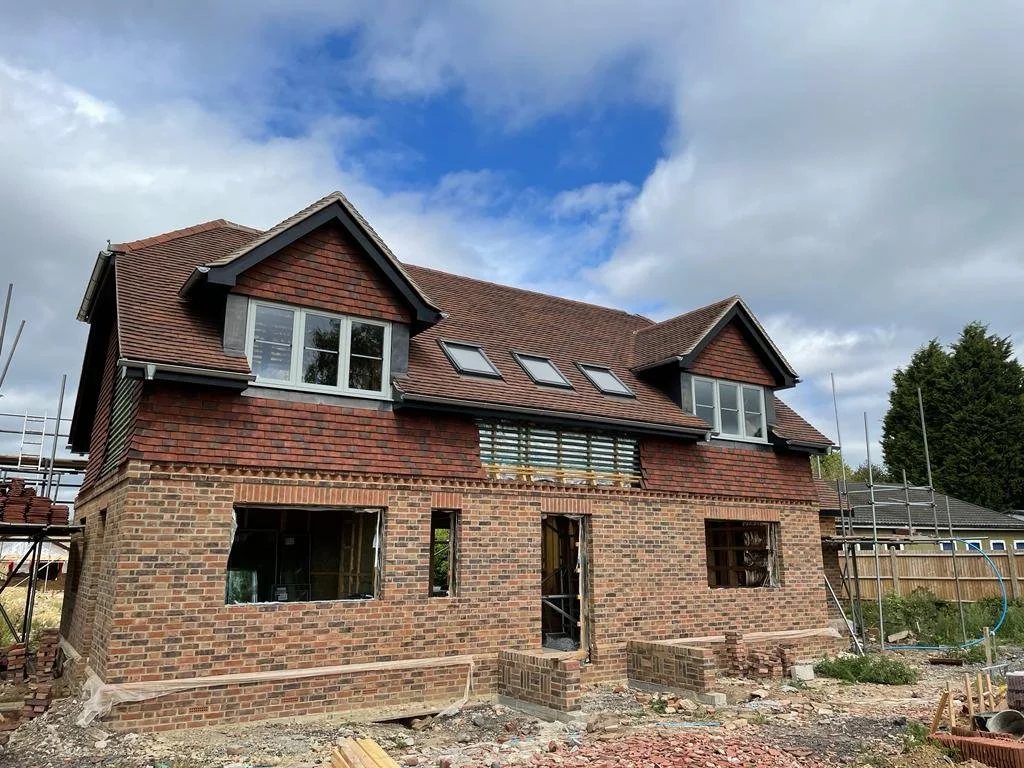 A completed brick home with dormer windows under a blue sky