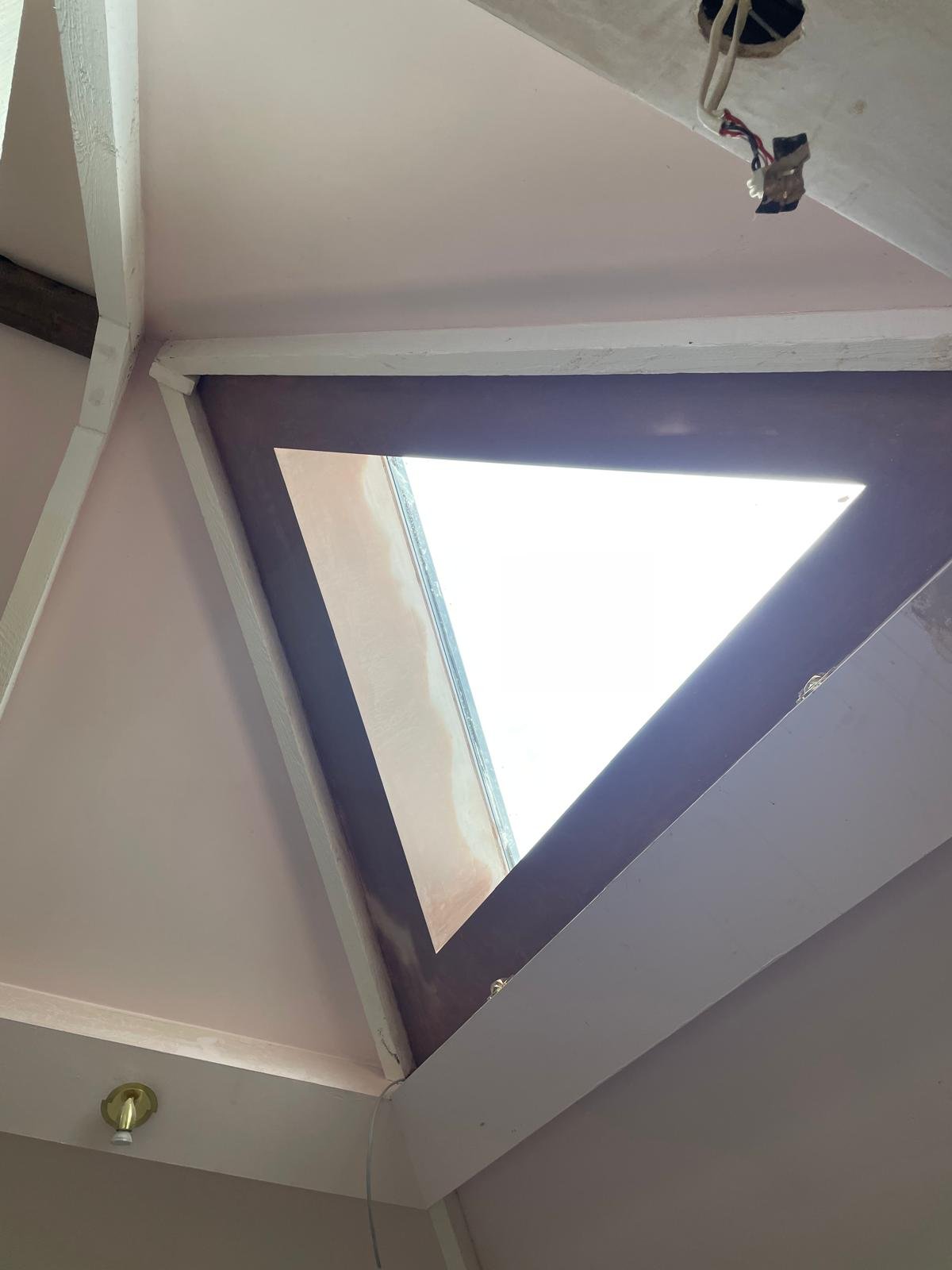 A triangular rooflight set into a vaulted plastered ceiling, letting daylight into the room below