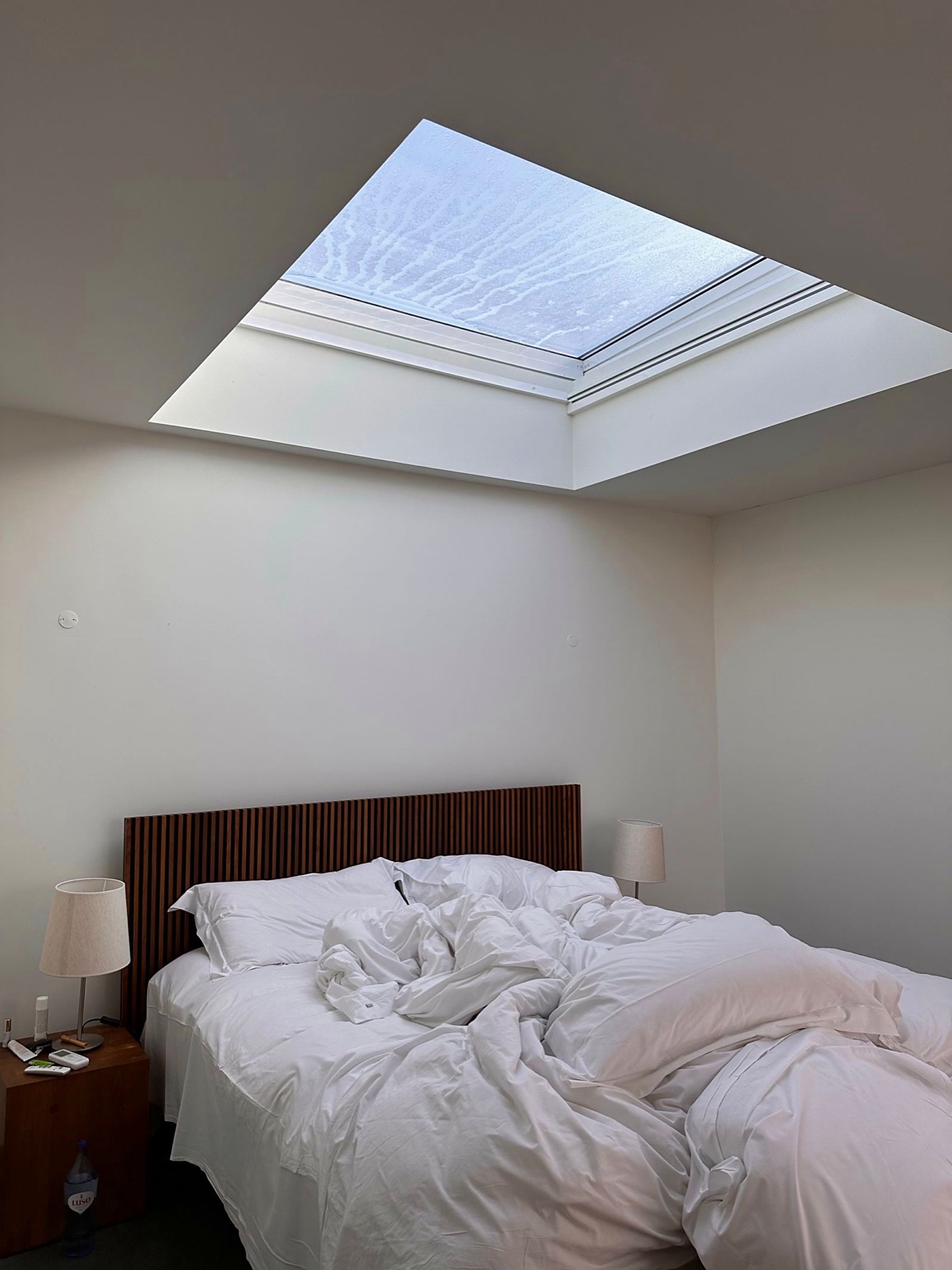 A loft bedroom with a large flat rooflight set into the ceiling above the bed