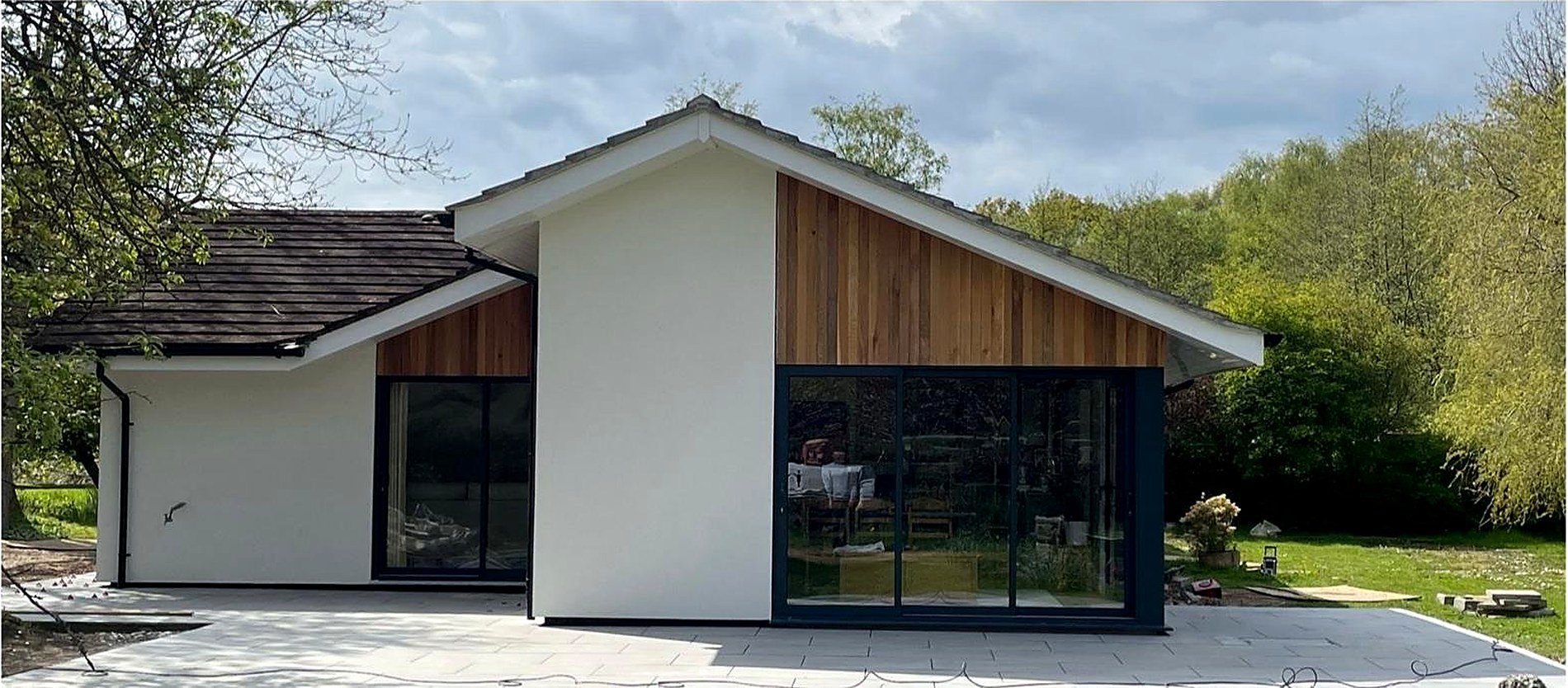 A fully refurbished Surrey home by I.C Developments, white render and cedar cladding with full height glazing onto the garden